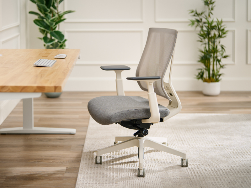 Office chair with a mesh backrest, adjustable armrests, and a padded seat beside a desk.