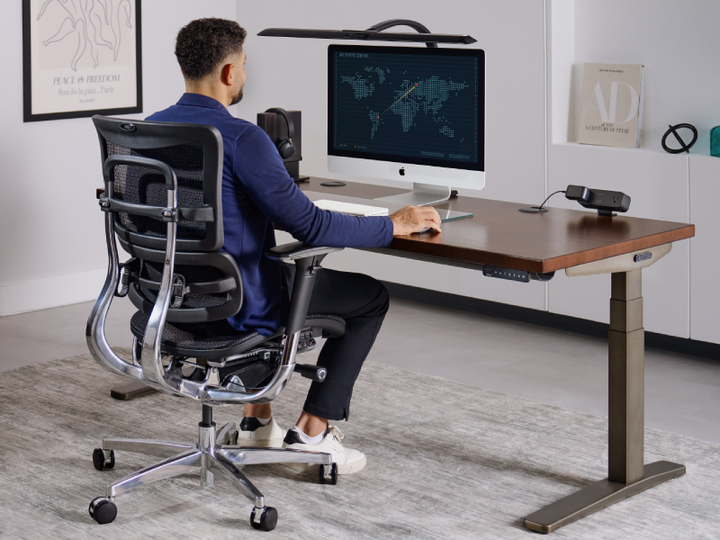 Man typing at a standing desk set to elbow height with his forearms level.