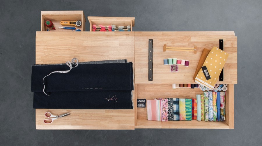 Top-down view of the UPLIFT Craft Table with drawers and compartments open and filled with sewing supplies.