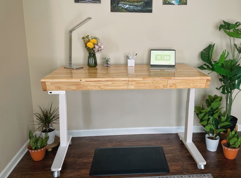 UPLIFT Craft Table with a white frame in a home studio with a task light, laptop, and standing mat.