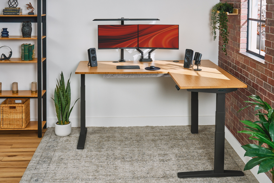 UPLIFT L-Shaped Standing Desk in a room with matching auxiliary furniture.