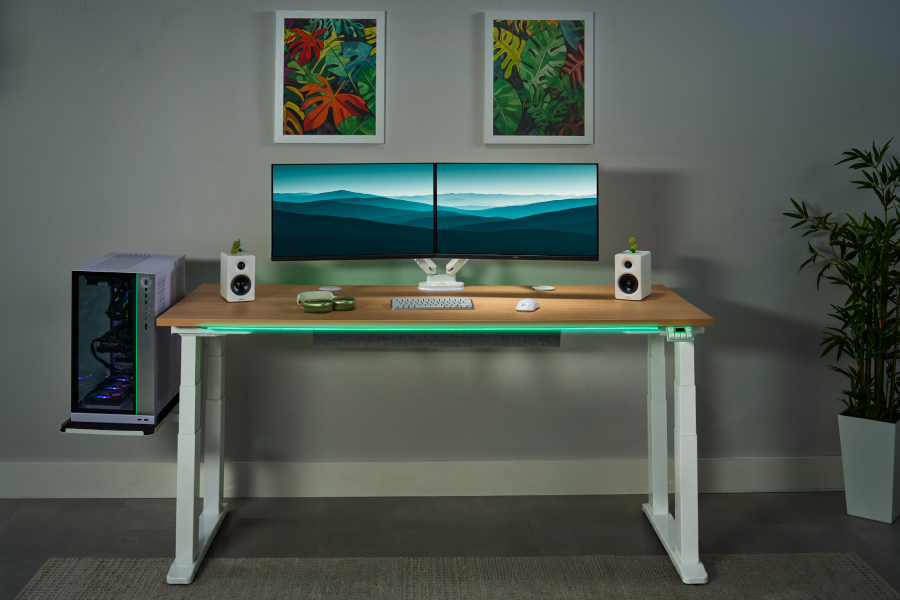 UPLIFT 4-Leg Standing Desk holding multiple monitors and a desktop PC.