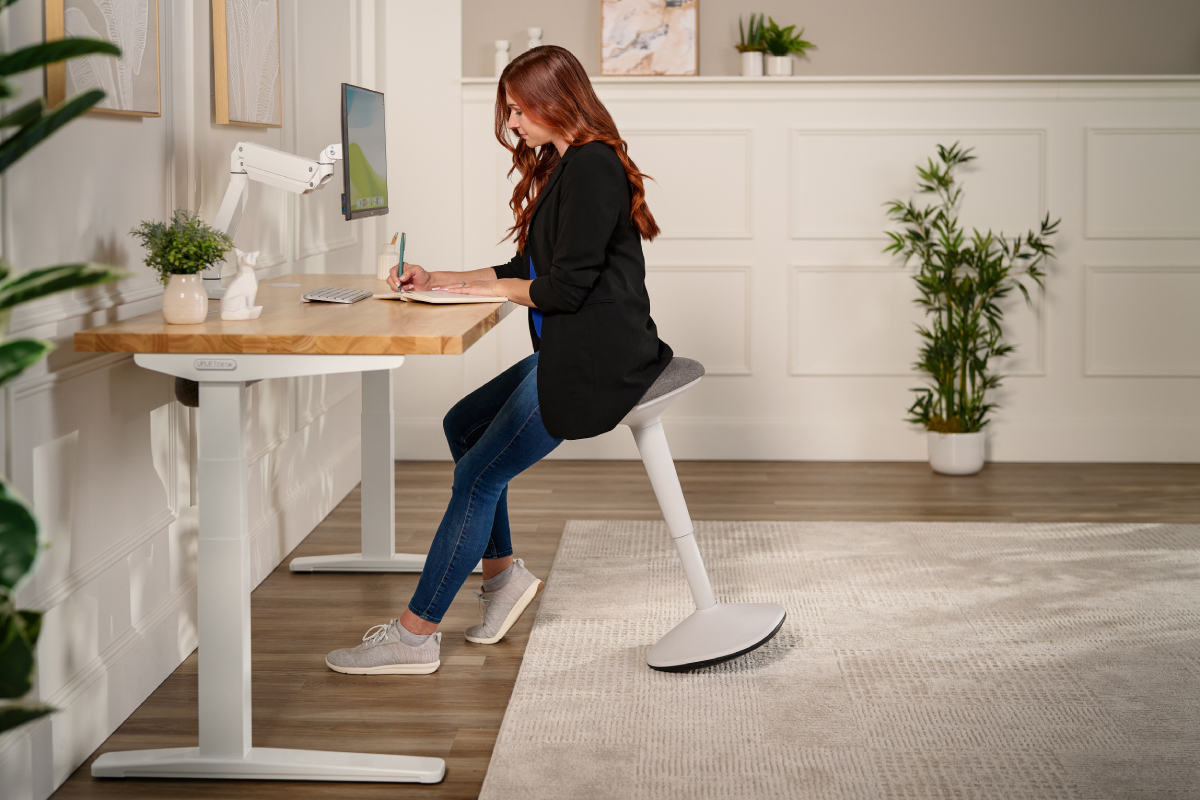 Ergonomic stool beside a height-adjustable standing desk.