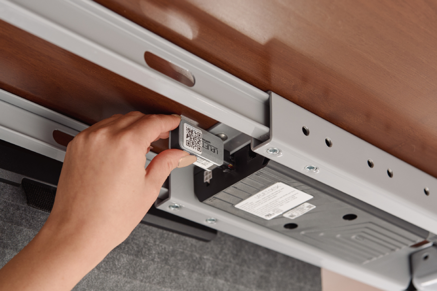 A hand plugs the UPLIFT Desk Bluetooth Adapter into the F port on a desk control box.