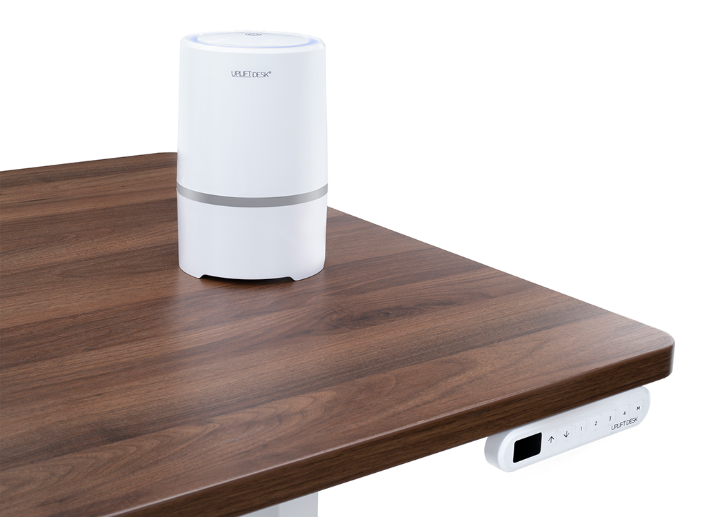 UPLIFT Desktop Air Purifier on walnut UPLIFT Standing Desk with white Advanced Keypad