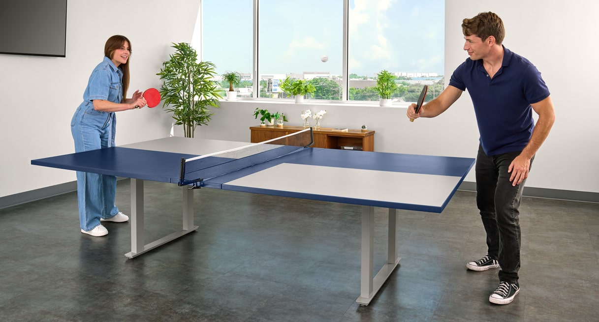 Two office workers playing ping pong on a UPLIFT Conference Table.