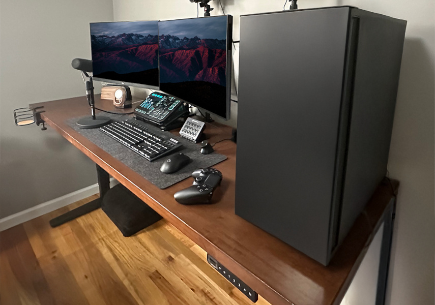 Dark rubberwood UPLIFT Standing Desk with monitors and accessories showing desk frame weight capacity.