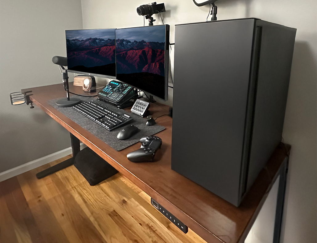 Dark rubberwood UPLIFT Standing Desk with monitors and accessories showing desk frame weight capacity.