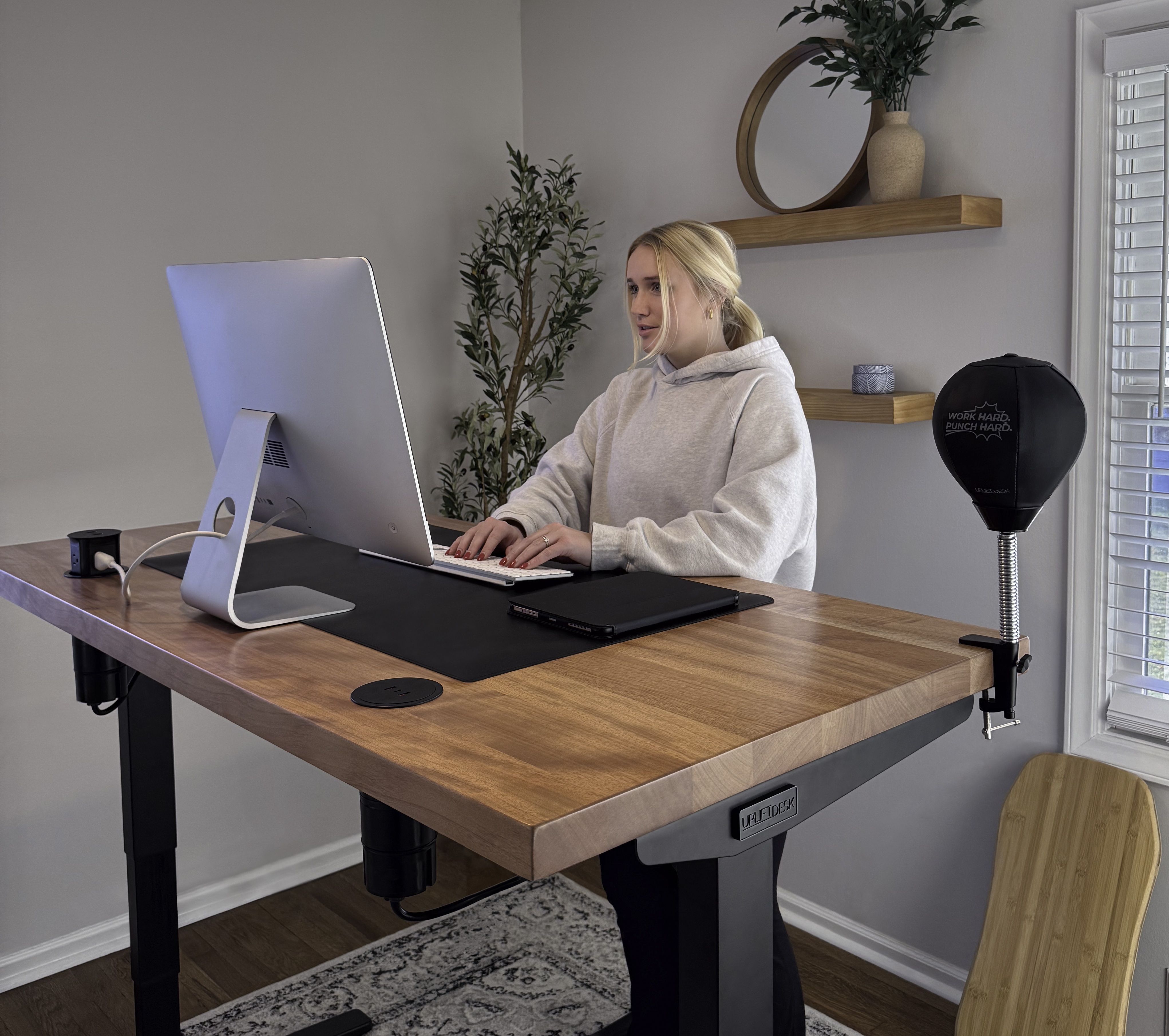 A woman working at an UPLIFT Desk featuring various desk accessories from UPLIFT Desk.