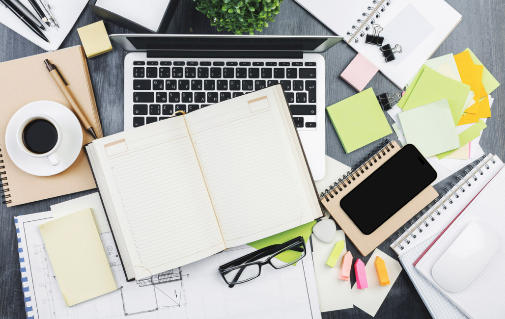 Overhead view of a desk cluttered with various items.