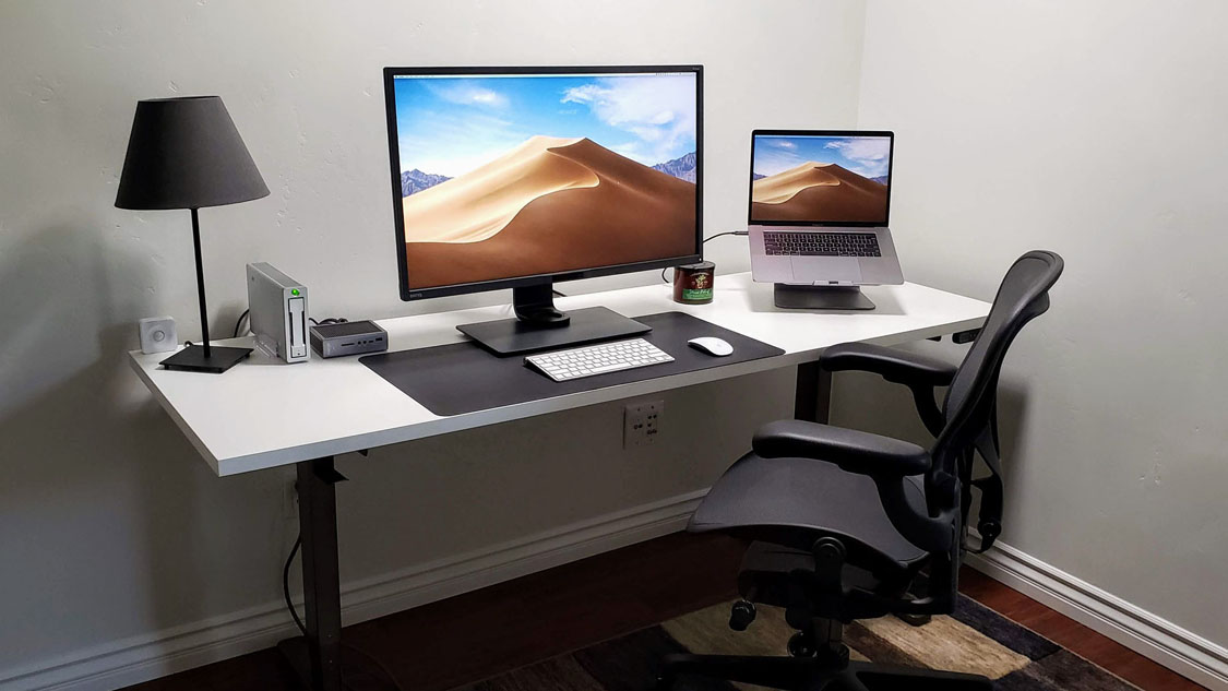 UPLIFT Laminate Standing Desk featuring a white laminate top and various desk accessories.