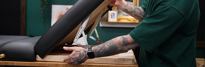 Tattoo artist meticulously working on a client's arm in a studio.