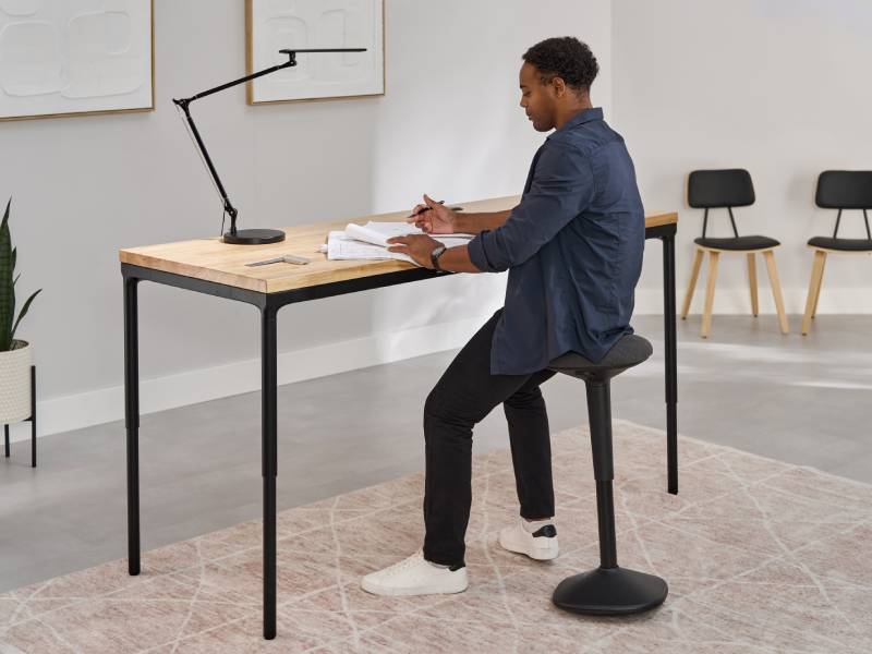Person sitting at an UPLIFT Parsons Standing Desk in modern home office setting