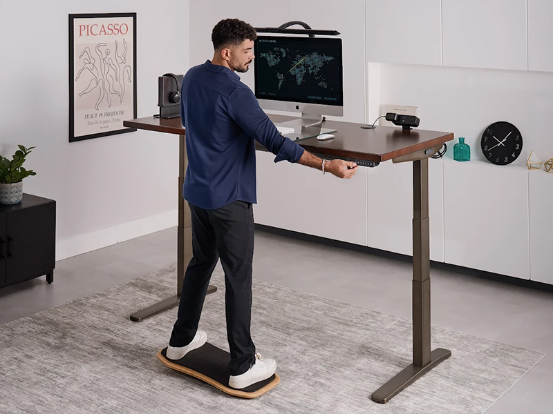Person working at an ergonomic standing desk by UPLIFT Desk.
