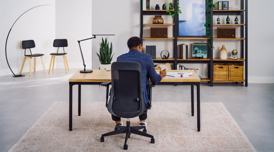 Man working at an UPLIFT desk in a three-posture workspace setup