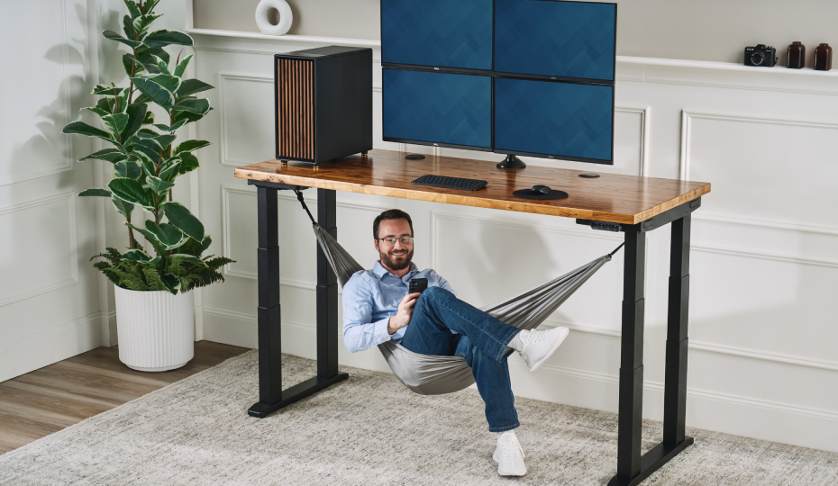 Person seated in their under-desk hammock beneath an UPLIFT standing desk