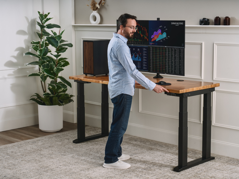 Man standing at a height-adjustable desk, adjusting the height using the keypad
