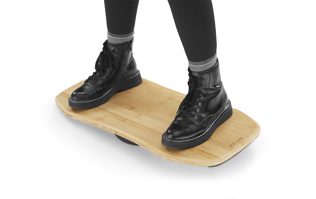 A woman standing on top of a Bamboo Motion X-Board by UPLIFT Desk