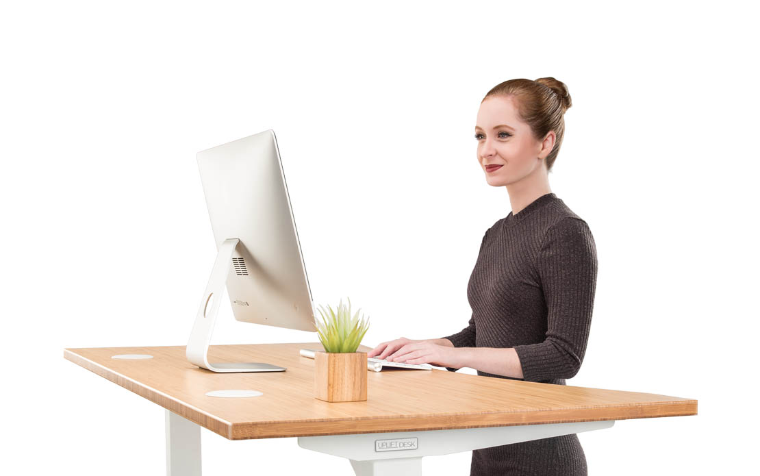 A woman stands at her UPLIFT Desk bamboo with her ear piece in helping customers