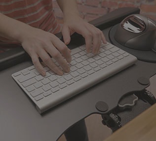 woman tasks comfortably at a standing height adjustable desk by UPLIFT Desk