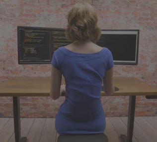 woman tasks comfortably at a standing height adjustable desk by UPLIFT Desk